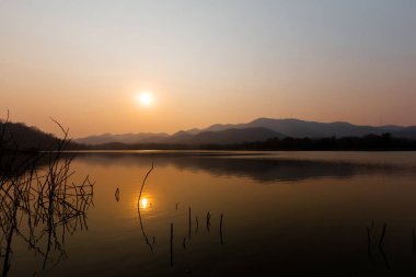 Güneş dağ manzaralı güzel rezervuar ile düşüyor