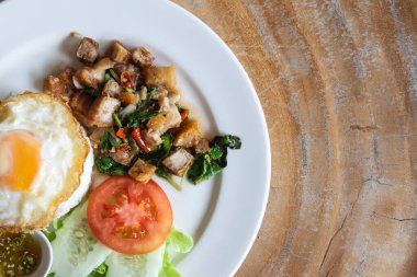 Kızarmış domuz ve fesleğenli pilav üzerine bir tabak ve kızarmış yumurta.