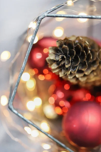 Noel süsleri, ışıklar, atmosfer. Kırmızı arka plan. Çam kozalağı. Kırmızı topları. Yeni yıl. 