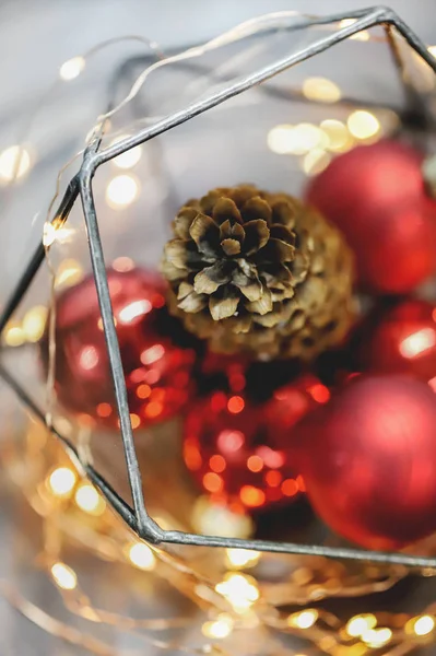 Noel süsleri, ışıklar, atmosfer. Kırmızı arka plan. Çam kozalağı. Kırmızı topları. Yeni yıl. 