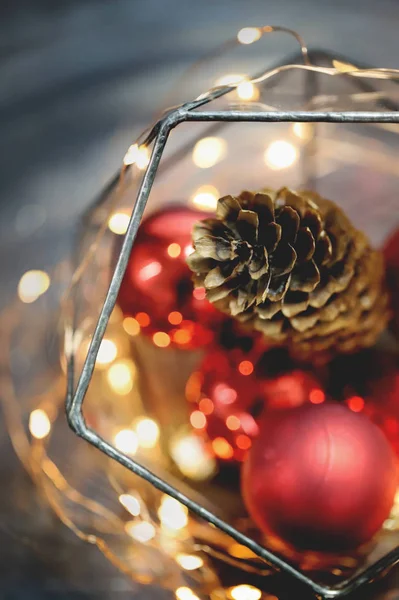 Noel süsleri, ışıklar, atmosfer. Kırmızı arka plan. Çam kozalağı. Kırmızı topları. Yeni yıl. 