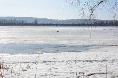 Bir adam erken bahar Nehri üzerinde kış balıkçılık yapan