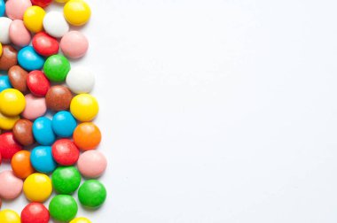 Beyaz arka planda renkli şeker topları. Çikolata şekerleri çok renkli şeker jölesiyle kaplıdır. Metin için yer