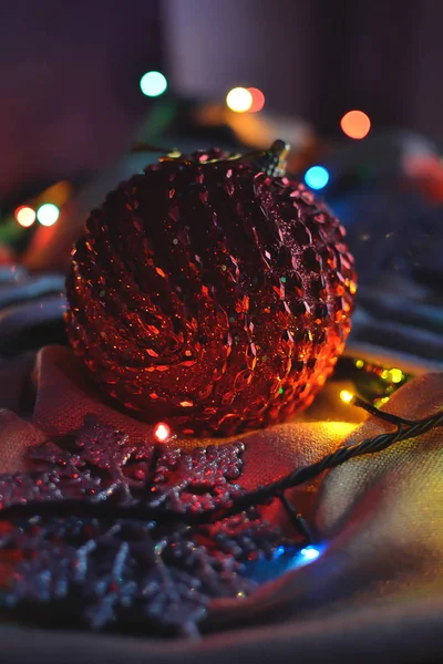 Bola vermelha de Natal e decorações nas luzes de uma grinalda — Fotografia de Stock