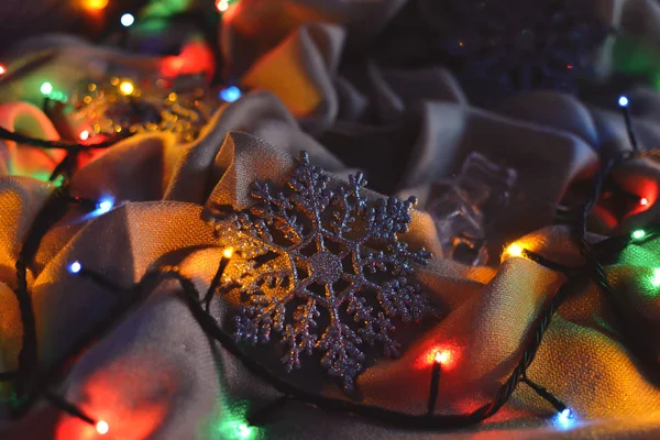 Decorazioni natalizie in argento fiocco di neve nelle luci di una ghirlanda — Foto Stock