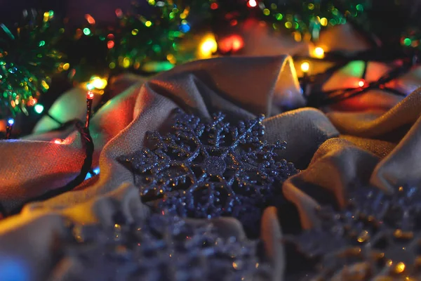 Tre scintillanti fiocchi di neve argentati, decorazioni natalizie alle luci di una ghirlanda — Foto Stock