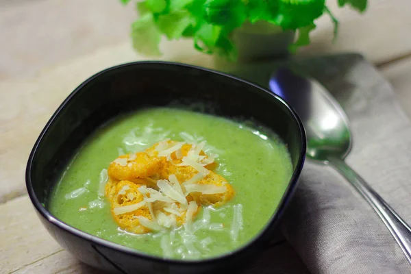 Fresh mashed soup with broccoli and green beans in black plate on wooden background — Stock Photo, Image