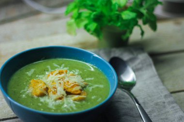 ahşap bir arka plan üzerinde mavi bir tabakta brokoli ve yeşil fasulye ile taze püre çorbası