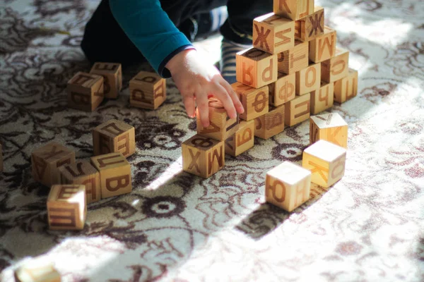 Une pyramide de blocs de bois et le concept de loisirs pour enfants-un petit garçon jouant sur le sol — Photo