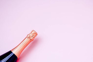 pembe arka plan üzerinde köpüklü şarap şişesi. tatil kutlamak için şampanya kapalı şişe