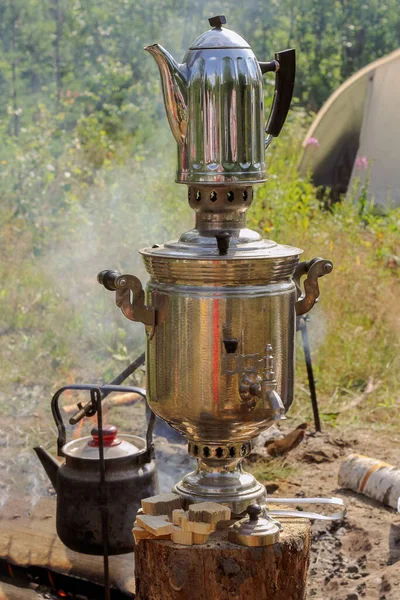 outdoor recreation in a campsite after a hike, making tea on the fire, a samovar on the street kindled with coal.