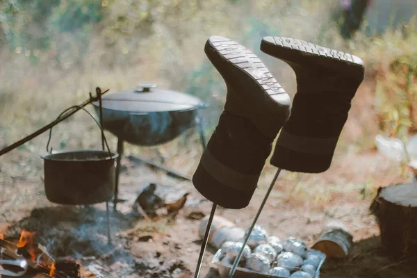 camping in nature after a hike, cooking in a pot over a fire, drying shoes. outdoor recreation. tourist weekends