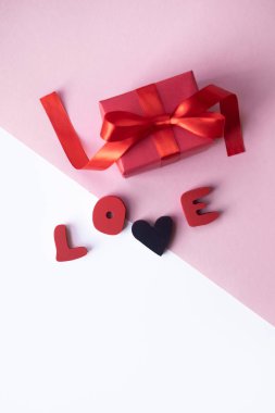 Aşk kelimesi hafif arka plan üzerinde kırmızı fiyonklu küçük hediye. Metniniz için boş alan.