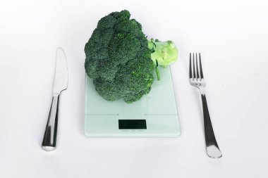 Brokoli elektronik mutfak ölçeklerde bıçak ve çatal beyaz arka plan üzerinde. Sağlıklı beslenme kavramı.