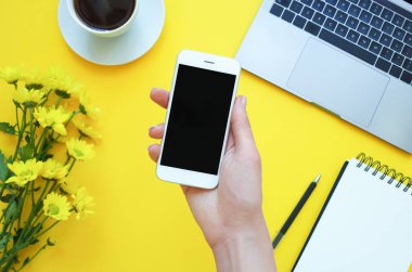 Tablo ofiste bir telefon tutan kadının el. Sarı arka plan