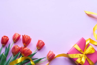 Pembe arka planda çiçekler ve kırmızı hediye kutusu. Boşluk Kopyala.