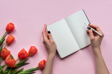 Bir defter üzerinde kadın el yazısı. Tulips ile pembe arka plan. Metniniz için yerleştirin