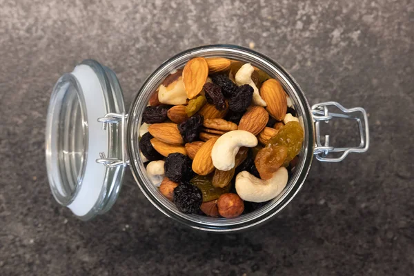 Koyu masa üzerinde cam kavanozda lezzetli organik farklı fındık. Sağlıklı gıda ve atıştırmalık.