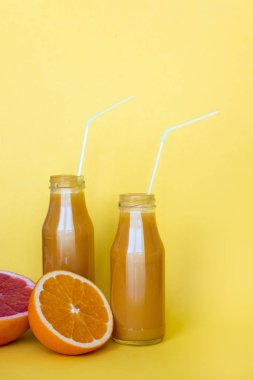 Sarı arka planda portakal ile taze portakal suyu. Kopyalama alanı
