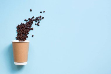 Mavi arka planda kahve çekirdeği ile kağıt kahve fincan. Kopyalama alanı