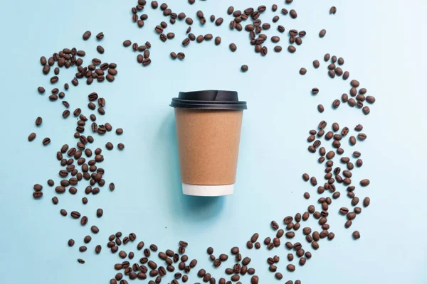 Coffee concept. Coffee beans with paper cup on blue background.