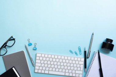 Dizüstü bilgisayar, dizüstü bilgisayar, gözlük, klavye, fotokopi alanı ile mavi arka plan üzerinde kalem ile Ofis masa masası