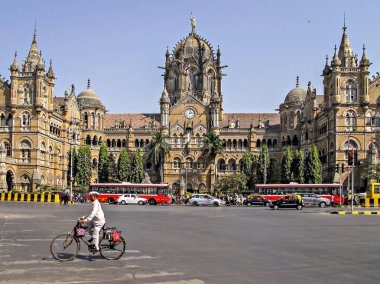 Bombay sefertası teslimatçısı Victoria Terminus Tren İstasyonu 'nun yakınlarındaki şehir trafiğinde bisiklet sürüyor. Mumbai, Hindistan-Şubat 01, 2018: Mumbai Dabbawala ve Victoria Terminus Tren İstasyonu Heritage binası 