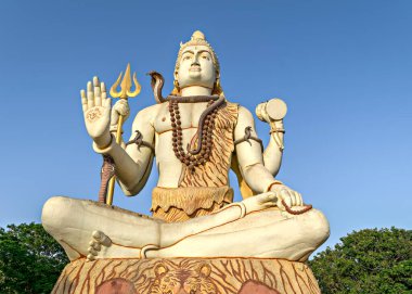 Hindu tanrısı Lord Shiva 'nın 82 feet yüksekliğindeki heykeli. Nageshwar Tapınağı, Dwarka, Gujrat, Hindistan' da açık mavi gökyüzü arka planına sahip..
