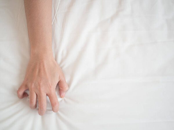 рука женщины тянет белые простыни в похоти и оргазме
.