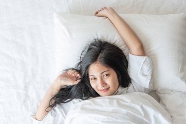 Mutlu, güzel Asyalı kadın, rahat ve mutlu bir şekilde yatakta yatarken uyuyor. Ev kadını yatak odasında uyukluyor.