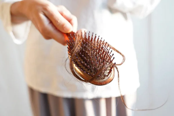 Mulheres com cabelos longos na escova de cabelo mostram problemas de perda de cabelo . — Fotografia de Stock