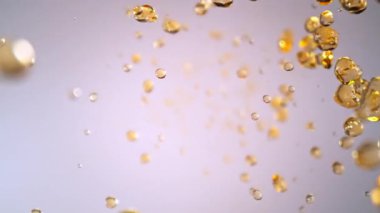 Hafif Arkaplanda Uçan Altın Sıvı Düşüşü 'nün Süper Yavaş Çekimi. Yüksek Hız Sinema Kamerası, 4K.