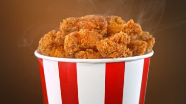 Slow Motion shot of Fried Chicken Pieces ve Smoke Rotting in a Bucket on Brown Background. Yüksek Hız Sinema Kamerası, 4K.