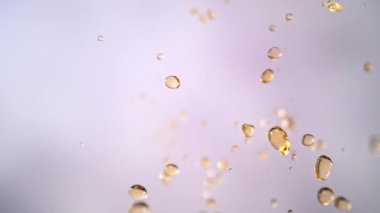 Hafif Arkaplanda Uçan Altın Sıvı Düşüşü 'nün Süper Yavaş Çekimi. Yüksek Hız Sinema Kamerası, 4K.