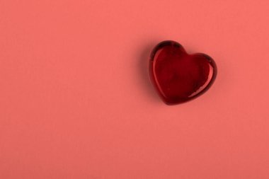 Sevgililer günü yaşayan mercan renkli arka plan üzerinde bir sembolü olarak kırmızı cam kalp