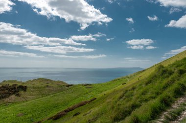 parlak mavi gökyüzü ve denizin yeşil çimenli hills