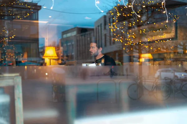 Handsome man with beard in coffee shop with lights reflecting Royalty Free Stock Photos