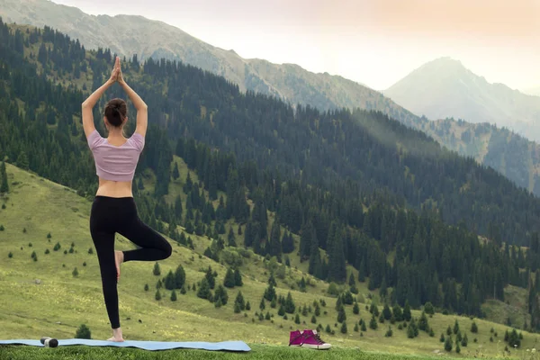 Yoga woman doing tree pose. Meditation and balance exercise in beautiful nature mountain landscape