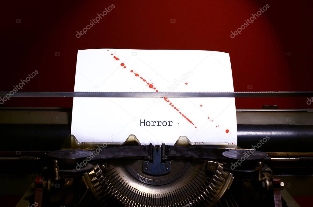 Typewriter spelling horror on paper with blood splashes