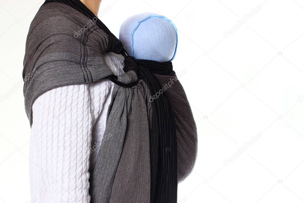 A newborn baby in blue hat in a ringsling baby carrier in vertical position