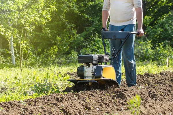 Un hombre arando tierra por cultivador de motor — Foto de Stock