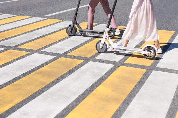 Patas de mujer y piernas de hombre caminando con scooter en cruce de caminos —  Fotos de Stock