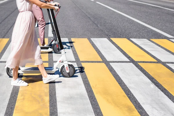 Patas de mujer y piernas de hombre caminando con scooters en cruce de caminos —  Fotos de Stock