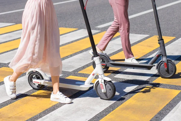 Woman legs and man legs walking with scooter on cross road