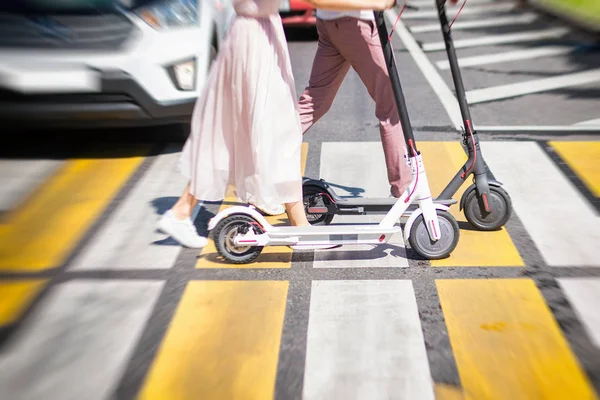 Pernas de mulher e pernas de homem andando com scooters na estrada transversal — Fotografia de Stock