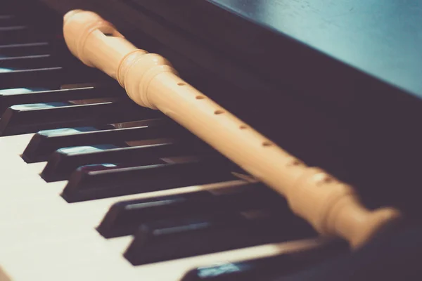 Block flute rest on a piano keyboard. classic music concept — Stock Photo, Image