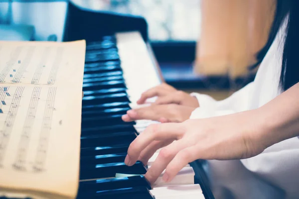 Opettaja opettaa pikkutyttöä soittamaan pianoa. Musiikin opiskelun ja luovan harrastuksen käsite, Perhe on kuva - Piano-näppäimistö ja lasten ja aikuisten musiikin soittamisen kädet — kuvapankkivalokuva