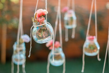 Bulanık bahçe arka plan ile asılı çiçekler ile Dekorasyon cam kavanoz. Yumuşak odaklama