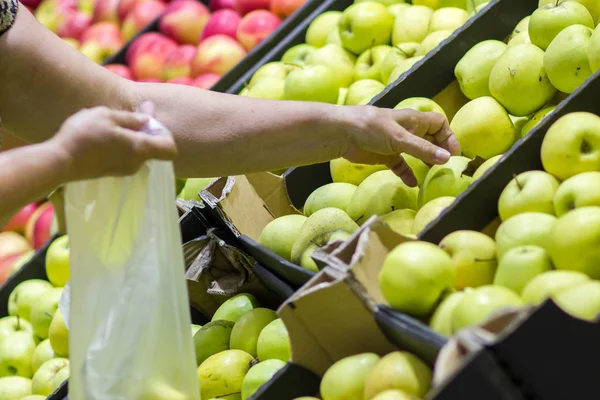 Alte Frau wählt frische Äpfel in Lebensmittelgeschäft produzieren Abteilung und legt sie in Plastiktüte. — Stockfoto