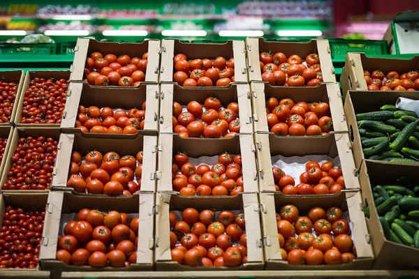 Schöne rote Tomaten in Kartons, zum Verkauf in einem Marktregal — Stockfoto
